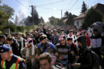 A Hungarian police officer leads a procession of refugees and migrants through a neighborhood in Hegyeshalom, Hungary. After 1,000 people arrived at the train station, they walked three miles to cross the border into Austria. Hungary has fumed over the influx of around half a million migrants and refugees into Europe this year, saying they present a security threat and competition for jobs.