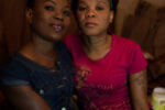 8/5/15 – Johannesburg, South Africa – Lufuno Nevhulaudzi poses for a picture with her friend, Yanga Mpengu, a two year resident, in her basement room at the Moth building in Joubert Park on Wednesday, Aug. 5, 2015. The residents here were evicted from their previous building in New Town to make way for a new mall under construction.