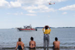 People watch as search and rescue crafts patrol along Carson Beach looking for Kyzr Willis.