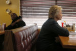 U.S. Democratic presidential candidate Hillary Clinton sits in a booth while visiting diners at the Belmont Hall Restaurant in Manchester, New Hampshire February 6, 2016.