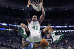 Boston Celtics center Al Horford hangs from the rim on a dunk against the Memphis Grizzlies in Boston.