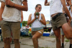 Gillian Wyman of Root 5 Farm in Fairlee, Vermont holds their team's mascot, "Broc" as she stretches before the start of the 2nd Annual Farmer Olympics.