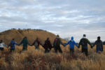 Protesters join hands in prayer at the end of the day's protest as police line the hill at Standing Rock during an ongoing dispute over the building of the Dakota Access Pipeline.