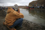 A man prays quietly across the river from Turtle Island as fellow protesters take to the other side.