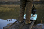 Police officers are reflected in the water as a protester stands on the edge of a bridge that had been dismantled by police earlier that morning. The secretary of the Army Corps of Engineers has turned down a permit for the construction of the controversial pipeline, but protesters remain cautious waiting to see what incoming President Donald Trump will do.