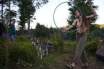 As dusk falls a rainbow family member spins a hula hoop at the edge of the meadow. Here the goal is to leave the outside world and all of it's trappings behind.