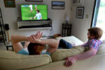 On a Saturday afternoon, Straus watches soccer on tv with his son Taylor DeLench who visits her often at her condo in Brewster.