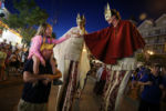 At Old Orchard Beach, Bo Pszeniczny and his daughter Camille, 5, greet stilt walkers Jalianne Li and Rose Maskery. Bo said, "we come here every year, this is her favorite spot. She chose Old Orchard Beach over Disney this year." He continued, We really enjoy the people, they're from all over. Everyone's friendly, everyone says hello. You can walk the beach at night..."