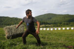 Merle Russell of Humble Hill Farm in Vershire, VT tosses a bail of hay as he takes part in the 2nd Annual Farmer Olympics held at Broad Acres Farm.