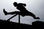 A competitor clears a hurdle during the boys 110 meter hurdles at the Div. 1 track & field championships in Somerville, Mass. Sunday, May 29, 2016.