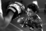 Boxing coach Russell Kimber works with student Rey Hance who was apprehensive at first to throw punches at Kimber.