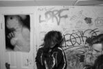 Girl dances by herself to unknown music with a strange poster on the wall. Unknown house venue, Allston.