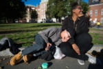 Liniște, left, a 22-year-old gay woman who is experiencing homelessness, laughs with her girlfriend Tay in the Boston Common on Oct. 10, 2016.