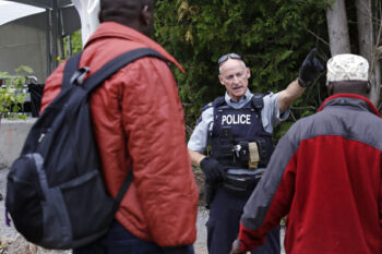 A Royal Canadian Mounted Police officer informs migrants that they will be arrested if they cross into Canada, and suggests using a legal border crossing about five miles away, at the end of Roxham Road in Champlain, N.Y., while heading to an unofficial border station across from Saint-Bernard-de-Lacolle, Quebec, Monday, Aug. 7, 2017. Officials on both sides of the border first began to notice last fall, around the time of the U.S. presidential election, that more people were crossing at Roxham Road.