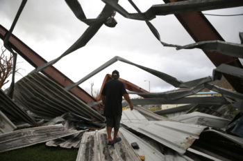 Yabucoa, Puerto Rico -- 9/29/2017 - In Yabucoa where Hurricane Maria first made landfall, the metal roof and viewing stands from a basketball court across the street were deposited onto Carmen Charriez's home. The family of five, including a nephew, rode out the storm by hiding in a hallway for hours. Nine days later they were still sleeping in plastic lawn furniture in their garage for fear of the damage done to their home.