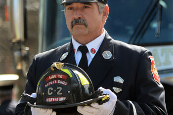 Watertown firefighter Lt.John Baccari carries the helmet of fallen Watertown firefighter Joseph Toscano, 54, during a s somber procession before firefighter Toscano's funeral at St. Patrick Catholic Church. (3/22/17)