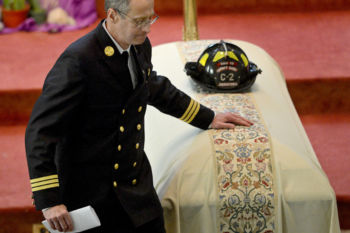 Watertown Deputy Chief Robert Quinn touches the casket of his friend and fellow firefighter Joe Toscano after delivering a eulogy Wednesday, March 22 at St. Patrick's Church in Watertown.