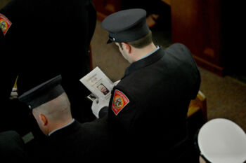 Watertown Deputy Chief Robert Quinn touches the casket of his friend and fellow firefighter Joe Toscano after delivering a eulogy Wednesday, March 22 at St. Patrick's Church in Watertown.