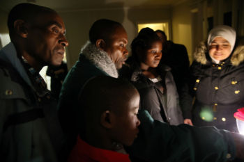 Sendegeya Bayavuge (left) and his family get instruction on how to use the stove. They had never used one before, and they watched in their new home Friday as a resettlement worker flipped the burners off and on.
They had never used a refrigerator, either. Or seen water pass through a faucet. Or been told how to lock a door. Or adjust a thermostat. Or even how to squeeze shampoo from a tube.