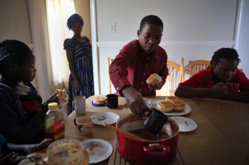 (Left to right) Nyirakabanza, her mother Vanisi, and siblings Dusenge, 15, and Maria, 17, have porridge after school. The family will receive a one-time $925 stipend per person from the federal government to help pay for rent and other basic necessities, but they are expected to become self-sufficient within six months.