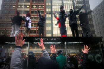 Fans jumped up on a bus stop in Copley Square as they line the route for the Patriots' 2017 Super Bowl victory parade.