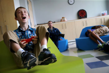 Connor played a Super Mario Brothers video game in the leisure center at the New England Center for Children in Southborough, MA. At the residential school for children with autism, even play time is an opportunity for adults to teach students social skills. Teachers talk through game strategy and cheer successful moves to encourage the boys to follow directions and to promote good sportsmanship.
Other schools may try a range of treatments, but NECC is wedded to applied behavior analysis, a patient but firm approach that breaks down desirable conduct into steps and rewards the child with something they badly want Ñ like iPad time Ñ for completing each one. It is an approach that has its critics, who think it too rigid, but here it seems often to work.