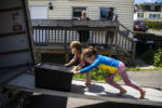 BIDDEFORD, ME - 07/13/2019 Siblings Laya, left and Evan Lupien push a tote up the ramp of the U-Haul while their parents, Mariah LeMieux-Lupien and Patrick Lupien, watch from the porch of their apartment. "More, more, more!" yells Laya, age three, after stacking the tote in the back of the truck. The children are accustomed to moving around as their parent's struggle to break through the glass ceiling of poverty in Southern Maine.
