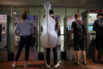 JULY 24, 2019: Cellist Mo Mo, from New York, purchases a ticket for the subway at South Station in Boston, Mass., United States. The New England Conservatory Alum visited friends in Boston.