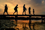 As the sun set, people walk along the iconic Sandwich Boardwalk which was first built in the 1870's and was rebuilt in the 1990's. Severe weather, including back to back Nor'easters in March of 2018 extensively damaged the bridge and the Town of Sandwich voted in 2018 to allocate $2million for long-term repairs.