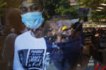 Women watch from inside a grocery store as demonstrators, reflected in the window, protest against racial inequality in the aftermath of the death in Minneapolis police custody of George Floyd in Boston, Massachusetts, June 10, 2020.
