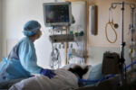 Worcester, MA - 12/10/2020: Registered nurse Winter Drury cares for a patient in the Covid-19 intensive care unit at UMass Memorial Medical Center in Worcester, MA. As the resurgent coronavirus rages across Massachusetts, intensive care units like this one again are filling with COVID patients. Many will stay for weeks, mostly alone, too ill to move, talk, or breathe on their own.