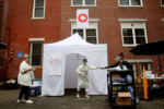 Boston, MA - 6/30/2020: Gia Brown, right, hands a test kit to nurse practitioner Dianne Valko at the NEW Health walk-up COVID-19 testing site in the North End neighborhood of Boston, MA.