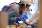 Worcester, MA - 12/10/2020: Registered Nurse Susan Frieda wears a PAPR (powered air-purifying respirator) while treating a patient in the COVID intensive care unit at UMass Memorial Medical Center in Worcester, MA. As they battle the pandemic again, nurses and doctors here wonder if people outside these walls truly understand the harsh reality they face day after day.
