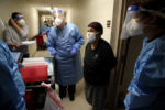 CENTRAL FALLS, RI - 12/30/2020: In neighboring Rhode Island, a team of volunteers talk with resident Awilda Santiago before administering the Moderna COVID-19 Vaccine in the hallway outside her home at Forand Manor in Central Falls, RI. With a cumulative COVID-19 rate of 16,815 per 100,000 people, Central Falls has been one of the hardest-hit areas in the Northeast.