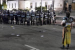 A protester stands off with police in riot gear outside the Kenosha County Courthouse, late Monday, Aug. 24, 2020, in Kenosha, Wis. Protesters converged on the county courthouse during a second night of clashes after the police shooting of Jacob Blake a day earlier turned Kenosha into the nationÕs latest flashpoint city in a summer of racial unrest.