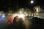 Protesters take cover from tear gas fired by police outside the Kenosha County Courthouse, late Monday, Aug. 24, 2020, in Kenosha, Wis. Protesters converged on the county courthouse during a second night of clashes after the police shooting of Jacob Blake a day earlier turned Kenosha into the nationÕs latest flashpoint city in a summer of racial unrest.