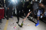 A protester places a bottle at the scene where someone was killed protesting last night the police shooting of Jacob Blake in Kenosha, Wis., Wednesday, Aug. 26, 2020.