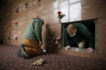 Everett, MA--12/10/20-- Crematory operator Jay Darling (R) climbs out of a tomb after guiding a casket inside of it during an entombment inside the mausoleum at Woodlawn Cemetery. During the worst of COVID, his crew was performing as many as 12 burials a day, four times the norm. They worked weekends, Giangregorio often enlisting laborers from the greenhouse or landscaping crews to help. And though the numbers have dipped from their springtime high, there is ominous winter news on the horizon, prompting worry that their macabre assembly line will once again kick up.