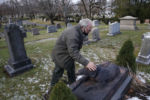 Everett, MA--12/10/20-- Alan Giangregorio pauses to pet the dog atop a grave at Woodlawn Cemetery. Giangregorio knows every story behind the historical markers in the cemetery like this one where the urban legend is that a man's dog wouldn't leave his grave after he died, when the dog passed away he was buried beside his owner.