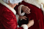 Sheila helps Dennis get his belt through a loop on the Santa suit Sheila created and stitched herself.