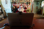 Santa Dennis waits in front of a background of Christmas decorations set up by Sheila, Dennis’s partner, waiting for a zoom call to connect.