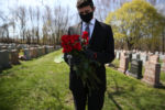 Malden, MA - 4/29/20 - Matt Tauro holds onto roses to give out to family members at Holy Cross Cemetery for Annette Nazzaro's funeral. Nazzaro, who lived to be 100, died of coronavirus or COVID-19.