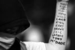 A demonstrator with the names of victims of police brutality written on their arm raises a fist at a Black Lives Matter protest at Peters Park in South End Boston on May 29, 2020.