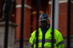 A Massachusetts State police officer stands behind the fence of the Massachusetts Statehouse and watches protesters on May 31, 2020.