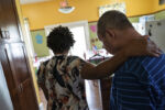 Sindy Micourt puts her hand on resident John Firman’s shoulder before helping him fix a snack at the Thrive Support and Advocacy center in Marlborough, MA on August 14, 2024.